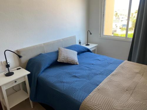 een slaapkamer met een bed met een blauw dekbed en een raam bij Apartamento LOLO in El Médano