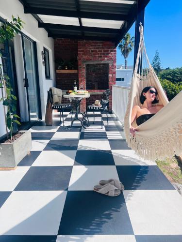 a woman sitting in a hammock on a patio at Salt & Pepper in Mossel Bay
