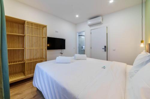 a bedroom with a large white bed and a tv at Atlantic Bliss in Albufeira