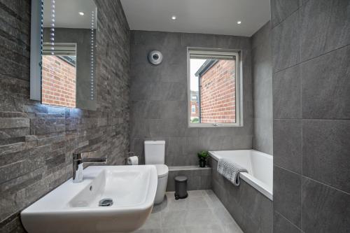 a bathroom with a sink and a bath tub at Spacious, High Spec & Modern House by Ark SA in Sheffield