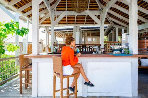 a woman sitting at a bar at a restaurant at Escape at Nonsuch Bay Antigua - All Inclusive - Adults Only in Gaynors