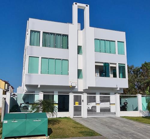 a large white building with a gate in front of it at Apto completo praia Caioba in Matinhos