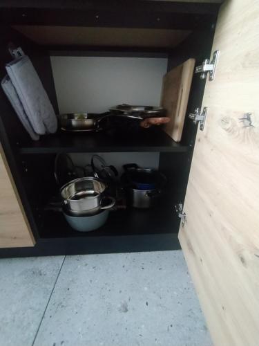 a cabinet with pots and pans in a kitchen at Kraken Apart in Kołobrzeg