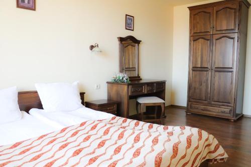 a bedroom with a bed and a wooden cabinet and a desk at Apartments & Studios Mountain Romance in Bansko