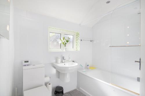 Baño blanco con lavabo y aseo en Cloud9 Accommodation, en Croydon