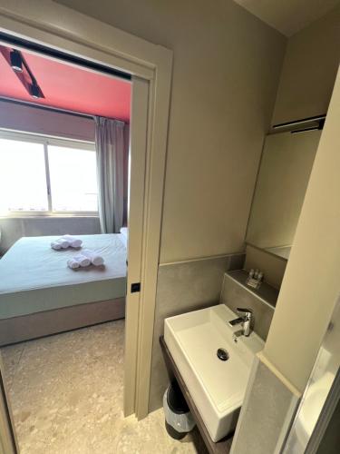 un bagno con un lavandino, un letto e uno specchio di Mia Suites Porto a Napoli