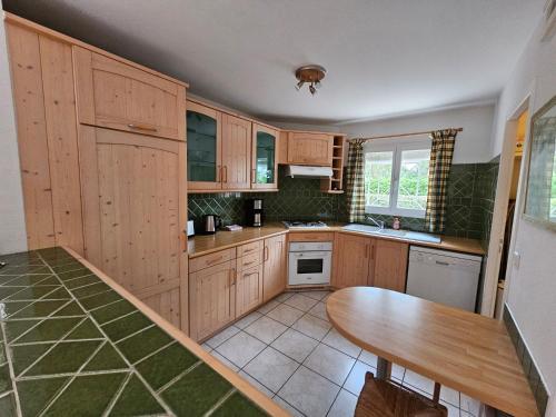 une cuisine avec des armoires en bois et une table en bois dans l'établissement Agréable maison climatisée idéalement placée pour 6personnes vieux boucau, à Vieux-Boucau-les-Bains