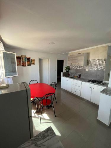 a kitchen with a red table and chairs in a room at Appartement la falaise in Monastir