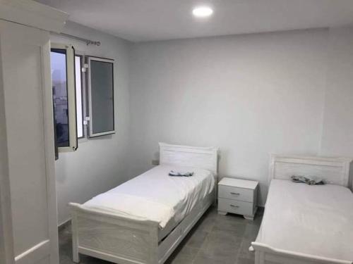 a white room with two beds and a window at Appartement la falaise in Monastir