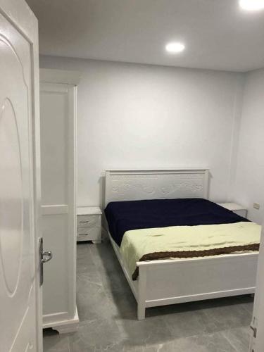 una camera con un letto bianco e una coperta blu di Appartement la falaise a Monastir