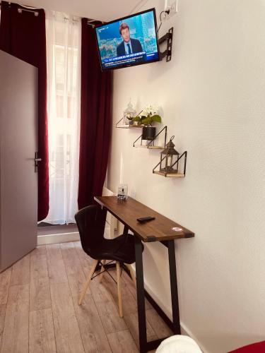 a room with a table and a tv on a wall at HOTEL LOUVAIN in Paris