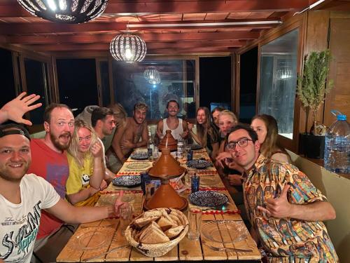 eine Gruppe von Menschen, die um einen Tisch sitzen in der Unterkunft Surf House Desert Point in Tiguert
