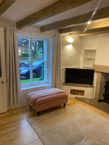 a living room with a large window and a flat screen tv at Jasmine Cottage in Gilling