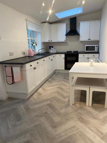 a kitchen with white cabinets and a white table at Jasmine Cottage in Gilling