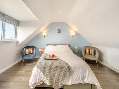 a bedroom with a bed and two chairs at Sea View Luxury 5 Star Cottage Near Milford Marina in Pembrokeshire