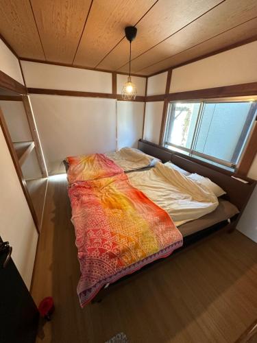 Bett in einem kleinen Zimmer mit Fenster in der Unterkunft Monster lodge 西伊豆 in Nishina