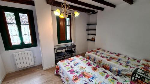 a bedroom with two beds and a table and two windows at Cal Gallo (Vivienda Vacacional) in Riosa