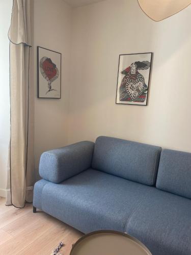 - un canapé bleu dans le salon avec des photos sur le mur dans l'établissement Charmant appartement, à Ajaccio
