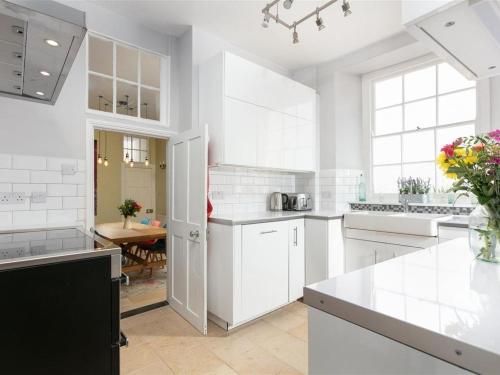 a white kitchen with white cabinets and a table at Marazion Beach Town House with Private Parking in Marazion