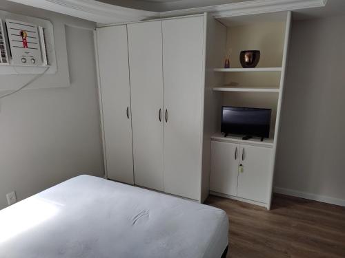 a white bedroom with a bed and a tv at BOA VIAGEM FLATS APTO 201 in Recife