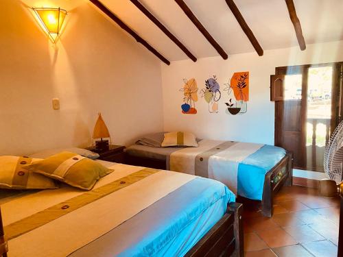 a bedroom with two beds in a room at Hostal Casa Ceiba in Barichara