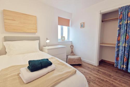 a bedroom with a large white bed and a window at BEACH SIDE Sea Shanty House in Trearddur