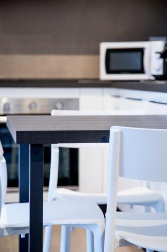 a table with two white chairs and a microwave at SUITE NAVIGLIO 26 in Parma