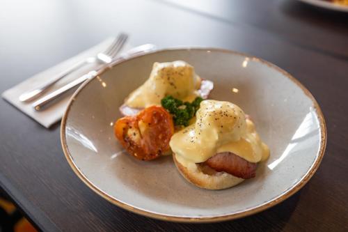 a plate of food with a hot dog and broccoli at Rydges Southbank Townsville in Townsville