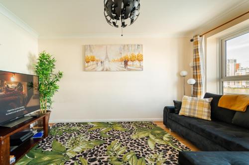 a living room with a couch and a window at Luxury Riverview 2Bed Apt- 5 mins from Excel London, Canary wharf, 02 Arena - Free Parking - PlayStation 4 Provided in London