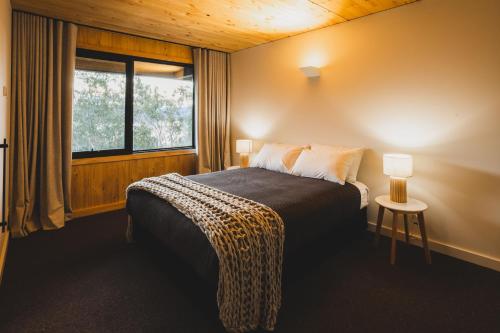 a bedroom with a bed with a window and a table at Kunama Townhouses in Jindabyne