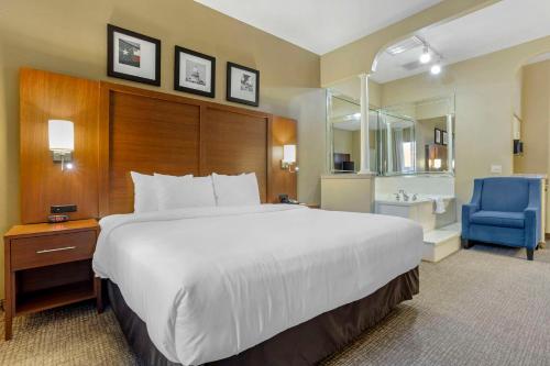 a hotel room with a large bed and a blue chair at Comfort Suites Houston NW - Vintage Park in Houston