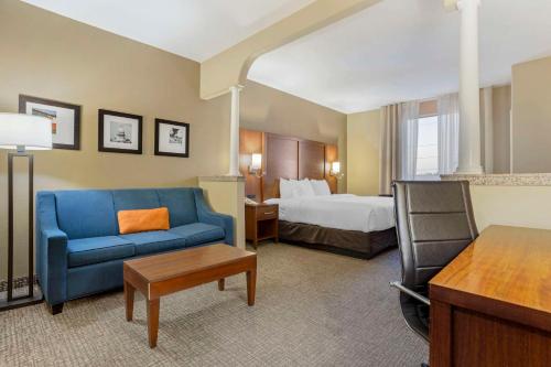 Habitación de hotel con cama y sofá azul en Comfort Suites Houston NW - Vintage Park, en Houston