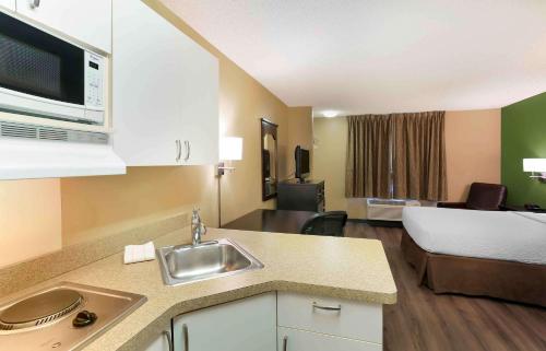 uma cozinha com um lavatório e um quarto com uma cama em Extended Stay America Suites - Salt Lake City - West Valley Center em West Valley City