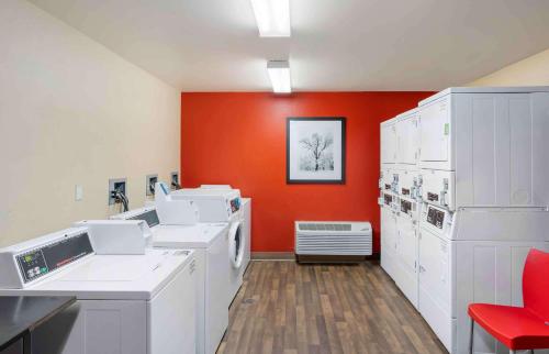 lavadero con electrodomésticos blancos y pared roja en Extended Stay America Suites - Santa Barbara - Calle Real, en Santa Bárbara