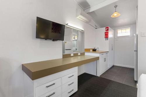 a kitchen with white cabinets and a flat screen tv at Econo Lodge East Adelaide in Adelaide