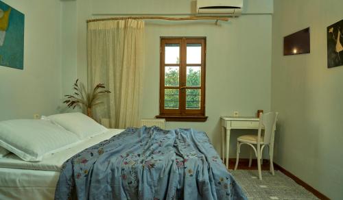 a bedroom with a bed and a table and a window at Thalassoxyla Portaria in Portariá