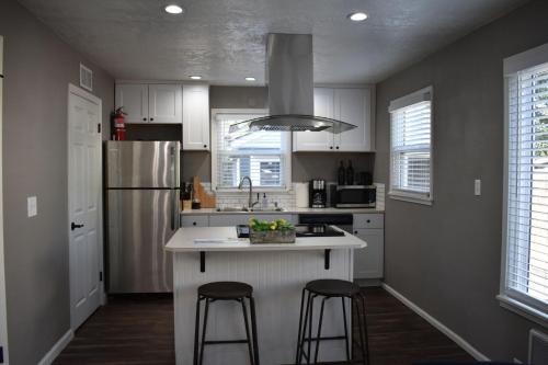 una cocina con armarios blancos y una isla con 2 taburetes. en Bsu Playland 3bd 1b Fully Remodeled on Bsu Campus en Boise