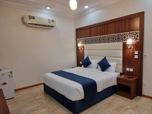 sypialnia z dużym łóżkiem z niebieską i białą pościelą w obiekcie الديار الفاخرة للشقق المخدومة w mieście Al Qunfudhah