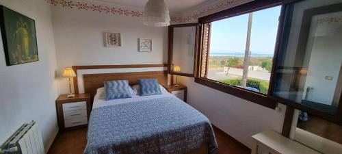 um quarto com uma cama com almofadas azuis e uma janela em Casa en la playa em Sagunto
