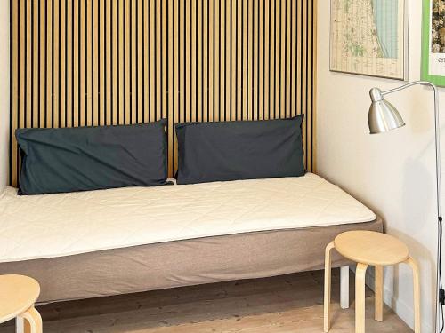 Apartment Hadsund IX في Hadsund: سرير مع اثنين من الوسائد الزرقاء وطاولتين