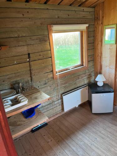 una cocina en una cabaña de madera con ventana en Lundby Camping, en Nibe