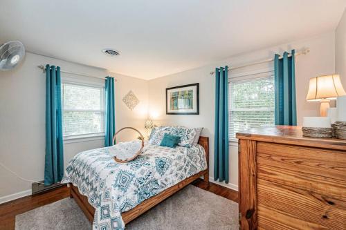 a bedroom with a bed with blue curtains and a dresser at Kelly's Comfortable Quinton Home in Quinton