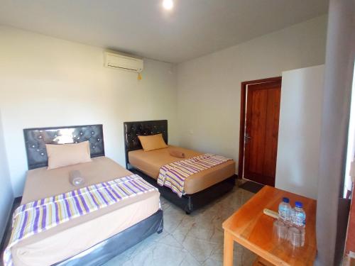 a bedroom with two beds and a wooden table at torok ocean homestay in Mataram