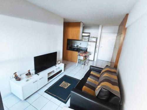 a living room with a black couch and a tv at Apartamento Praia de Ponta Verde com um quarto in Maceió