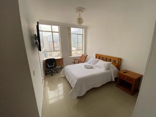 a bedroom with a bed and a chair and a window at (1902A) - Apto en el Corazón de la Ciudad con Vista Única in Bogotá