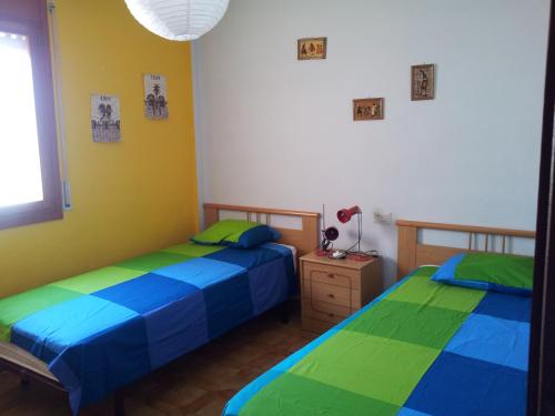 two beds in a room with yellow and blue at AMPOLLA in L'Ampolla