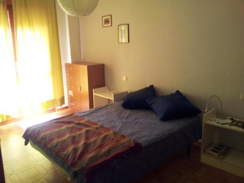 een slaapkamer met een bed met blauwe kussens en een raam bij AMPOLLA in L'Ampolla