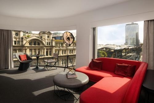 uma sala de estar com um sofá vermelho e uma grande janela em Hotel Indigo Melbourne on Flinders, an IHG Hotel em Melbourne