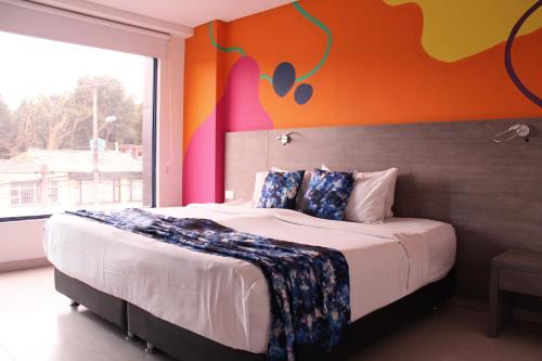 een slaapkamer met een groot bed met een oranje muur bij Agora Suites Self-Service Boutique Hotel in Bogota