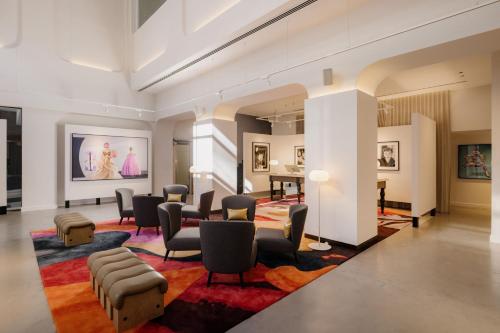 a lobby with a waiting room with chairs and paintings at Hotel Indigo Melbourne on Flinders, an IHG Hotel in Melbourne